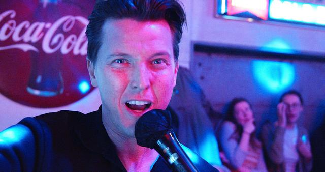 Male host belting into the mic at a Sing with the Stars night
