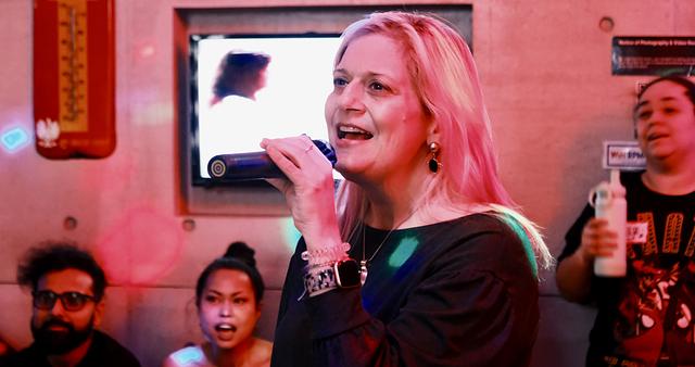 Broadway host singing into the mic at a Sing with the Stars night