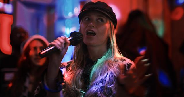 Guest in a cap singing into the mic at a Sing with the Stars night