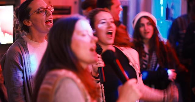 Four guests laughing together, drinks in hand, as one sings into the mic at RPM Underground